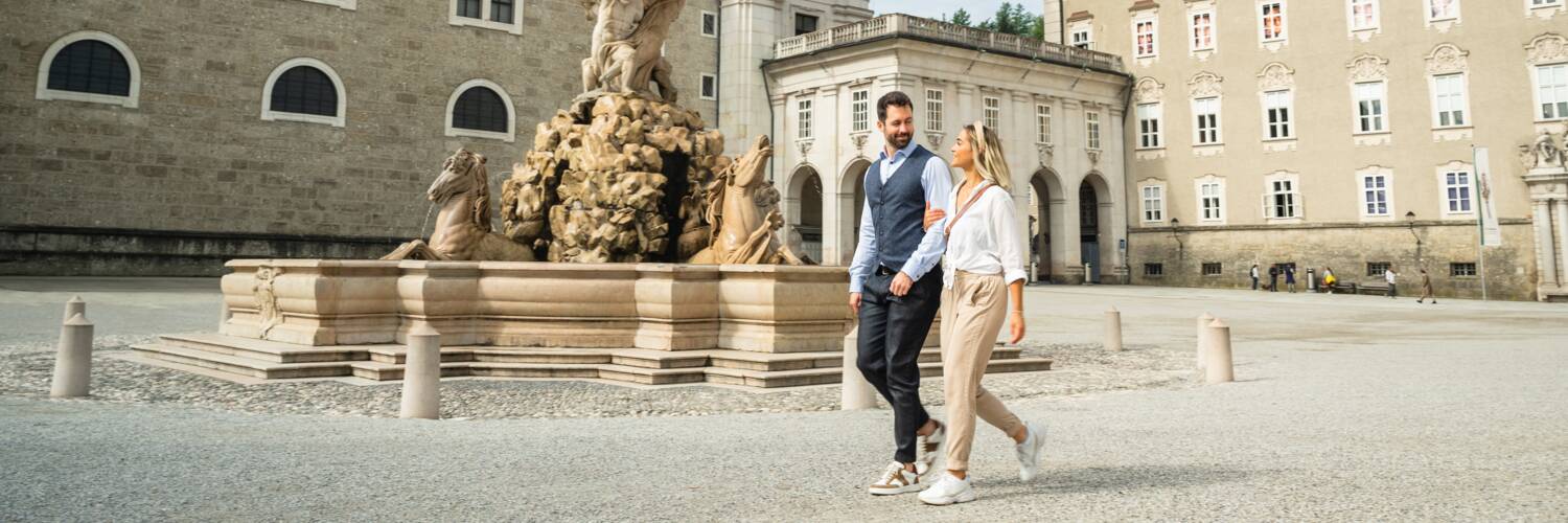 A couple walking across Residenzplatz Salzburg in Spring | © TSG Tourismus Salzburg GmbH / M. Kohlmayr