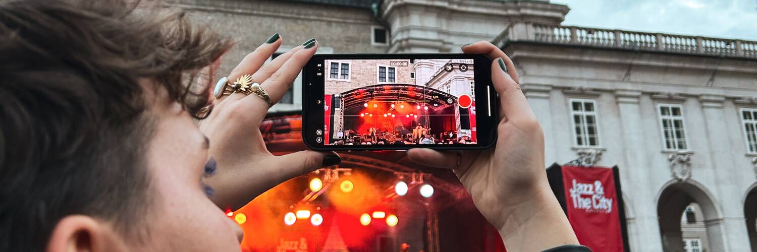 Eine Person, die mit einem Smartphone Content produziert am Kapitelplatz Salzburg. | © TSG Tourismus Salzburg GmbH, Tanner