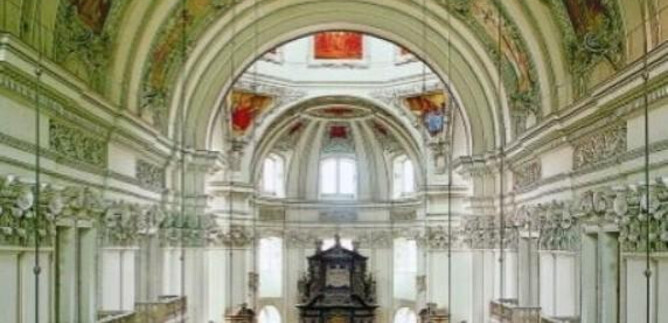 An impressive church with a high ceiling and ornate ceiling paintings. The interior view shows a symmetrical arrangement of pews and a lavish altar. | © Kunst & Kultur