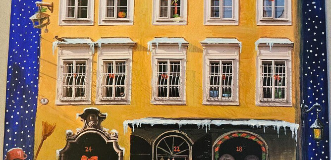 A festive city view with Mozart's birthplace in yellow. In front of the building, there is a snowman and a small Christmas decoration. | © ISM