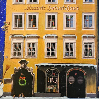 A festive city view with Mozart's birthplace in yellow. In front of the building, there is a snowman and a small Christmas decoration. | © ISM