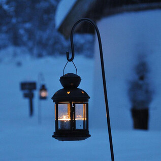 A beautiful lantern hangs in the cold, snowy landscape. The darkness is illuminated by its warm light. | © Salzburger Freilchtmuseum