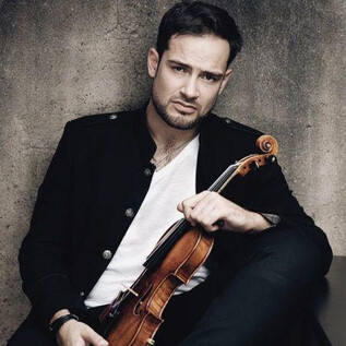 A man is sitting with a violin in his hand. He is wearing a black jacket and is looking seriously at the camera. | © recreation Event GmbH