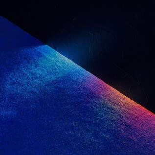 A mermaid sits in the waves of the ocean and looks pensively. Her long, red hair and a flower crown complete the mystical image. | © kunst-dokumentation.com