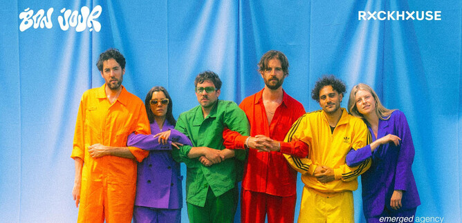 Six people stand in front of a blue background wearing colorful outfits in yellow, green, orange, and purple. They pose together and seem to radiate a cheerful atmosphere. | © Paul Vincent Schütz