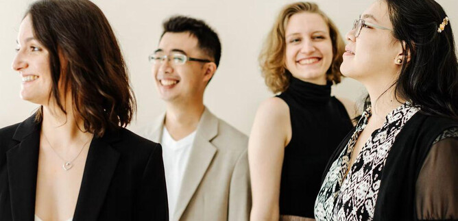 A group of four people stands together and smiles.  
They are wearing different and stylish outfits, creating a friendly and relaxed atmosphere. | © Theresa Pewal