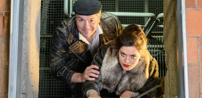 A man and a woman are climbing a staircase. The woman is wearing a fur coat and the man is wearing a leather jacket and a cap. | © SLT / Tobias Witzgall