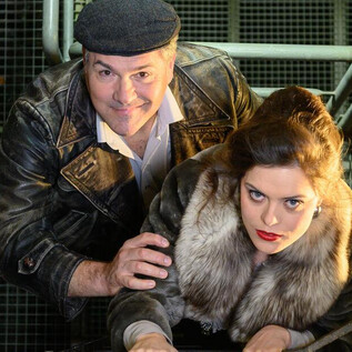A man and a woman are climbing a staircase. The woman is wearing a fur coat and the man is wearing a leather jacket and a cap. | © SLT / Tobias Witzgall