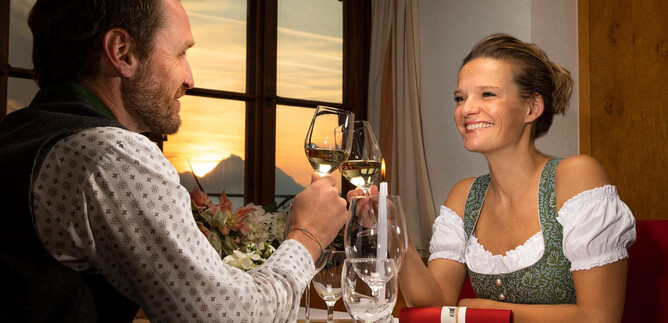 A romantic dinner at sunset. A man and a woman toast with glasses, while cozy table decor is visible in the background. | © Salzburg Highlights