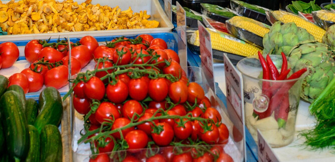 A colorful market with fresh vegetables and fruits. In the foreground are red tomatoes, zucchini, and green bell peppers. | © Tourismus Salzburg GmbH, Breitegger G.