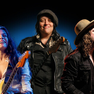 Three musicians stand on stage, each with an electric guitar. The atmosphere is lively and musical, ideal for the Blues Caravan 2026. | © Rockhouse Salzburg