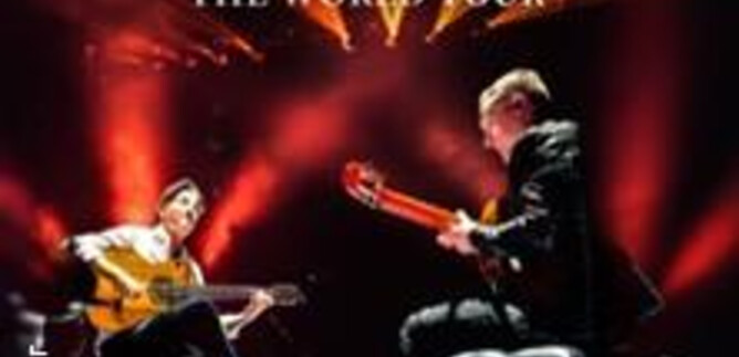 Two musicians are playing guitar on a stage with intense lighting. In the background, the sign reads “Café del Mundo Guitarrize - The World Tour.” | © Alex Ander