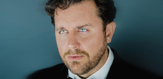 A well-dressed man in a suit with a bow tie. He looks thoughtfully into the distance with an intense gaze. | © Marco Borelli