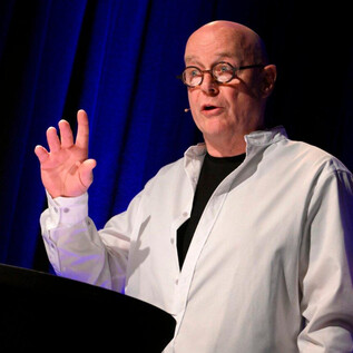 An older man with glasses is speaking in front of an audience. He raises his hand while making an important statement. | © Peter Kainrath / Gerry Lobenwein