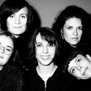 A group of five women poses together in a black-and-white photo. They all have different hairstyles and are wearing black clothing. | © Apollonia Theresa Bitzan