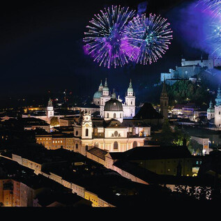 A stunning city view at night with colorful fireworks. In the background, historic buildings and an impressive fortress can be seen. | © SLT / Anna-Maria Löffelberger