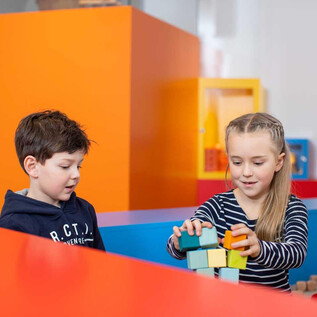 Two children are playing with colorful building blocks. They are smiling and building a tower together. | © Salzburg Museum/Neumayr