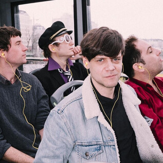 A group of four young people is sitting in a bus. They are listening to music and looking out the window. | © Ingo Pertramer