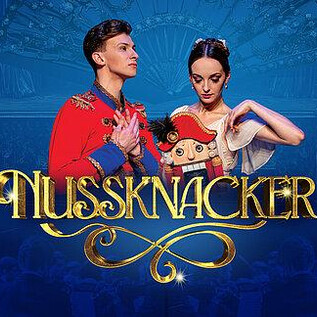 Two dancers in festive attire stand in the foreground. In the background, a festive atmosphere with blue tones and chandeliers can be seen, and the title "Nutcracker" is prominently placed. | © Ovation Events GmbH