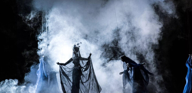 A mysterious stage performance with smoke and dramatic lights. The protagonist in an elegant costume draws attention to herself. | © georgeye