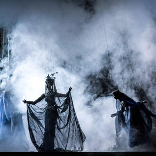 A mysterious stage performance with smoke and dramatic lights. The protagonist in an elegant costume draws attention to herself. | © georgeye