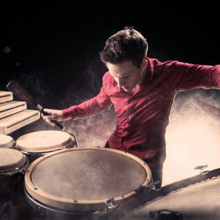 A musician passionately plays drums and percussion. The background is foggy, which enhances the energy of the performance. | © Stefan Sietzen
