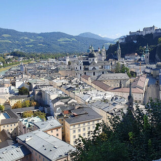 A picturesque view of Salzburg with historic buildings and the Hohensalzburg Fortress in the background. The mountains and blue sky complete the beautiful landscape. | © Wienerroither Sylvia