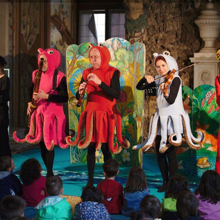 Eine Aufführung mit Schauspielern in bunten Kostümen als Tintenfische. Kinder sitzen im Publikum und schauen gespannt zu. | © Jeunesse