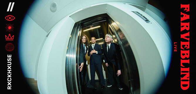 Three people in elegant suits are standing together in an elevator. The elevator has a modern, metallic green appearance. | © Noemi Kapusy