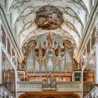 A magnificent church with an impressive organ and ornate ceiling frescoes. The walls are richly decorated and convey a solemn atmosphere. | © Hiva Naghshi