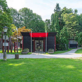 A modern building with a red roof in a green park.  
Surrounded by trees and paths, ideal for relaxing walks. | © Stadt_Salzburg