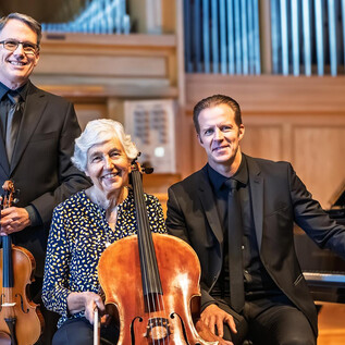 Drei Musiker stehen in einem Konzertsaal. Sie halten Instrumente und lächeln in die Kamera. | © Barbara Thiem