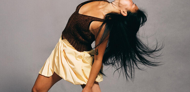 A dancing woman with long hair and a dress. She moves dynamically in front of a gray background. | © Chris Rogl