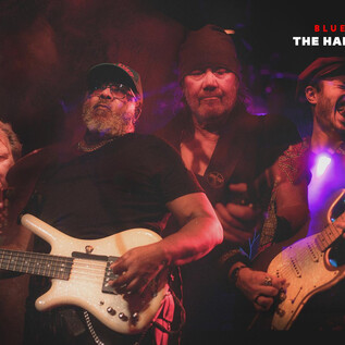 A band is playing live on stage. The musicians have passionate expressions and are holding their instruments in their hands. | © mike catches light