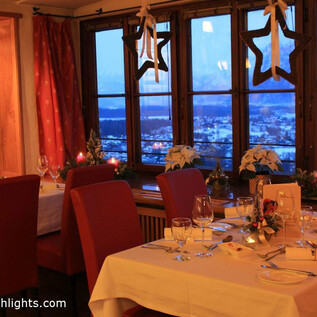 A cozy restaurant with nicely set tables and a view of the mountains. The warm lighting creates a pleasant atmosphere. | © salzburghighlights