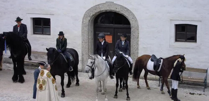 A group of riders stands in front of a historic building. They are riding various horses, including a gray one and a brown one. | © Salzburg Burgen & Schlösser