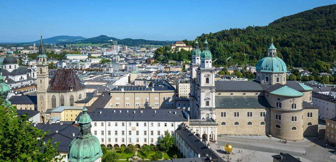 An impressive view of the city of Salzburg with its historic buildings and green hills. The clear sky and the architecture create a picturesque scene. | © TSG Toursimus Salzburg