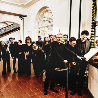 A group of people in formal clothing stands in a hallway and smiles. They seem to be waiting for something and have a cheerful atmosphere. | © Mario Balzi