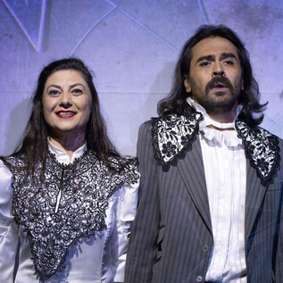 Two actors in historical costumes stand next to each other on stage. They have both cheerful and serious expressions. | © Florian Koller Mistura
