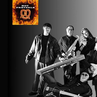 Eine Band steht zusammen und posiert für ein Foto. Sie halten Musikinstrumente und tragen schwarze Kleidung. | © Rockhouse Salzburg