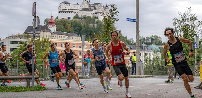 Un groupe de coureurs participe à une course, tandis qu'un impressionnant château est visible en arrière-plan. L'atmosphère est sportive et dynamique. | © Jedermannlauf