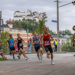 Un groupe de coureurs participe à une course, tandis qu'un impressionnant château est visible en arrière-plan. L'atmosphère est sportive et dynamique. | © Jedermannlauf