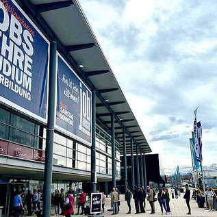 A large exhibition hall with posters about jobs, apprenticeships, and studies. Many people are standing in front of the entrance and it is cloudy. | © BARLAG werbe- & messeagentur GmbH