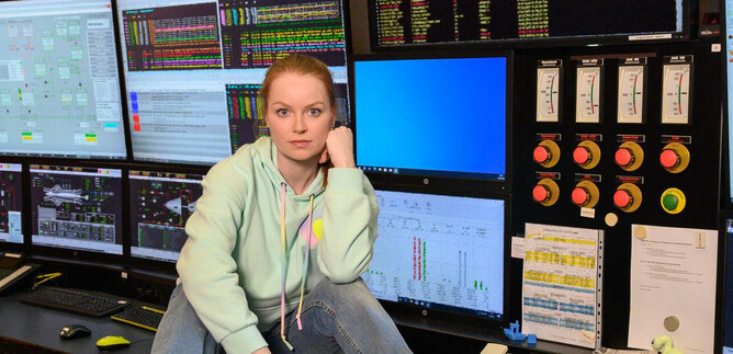 A person is sitting at a control panel with several screens. The screens display various data and graphics. | © SLT / Tobias Witzgall