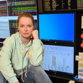 A person is sitting at a control panel with several screens. The screens display various data and graphics. | © SLT / Tobias Witzgall