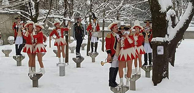 A group of musicians and dancers in winter clothing stands in a snowy environment. They present a festive performance while the landscape is covered with snow. | © 1. Salzburger Faschingsgilde