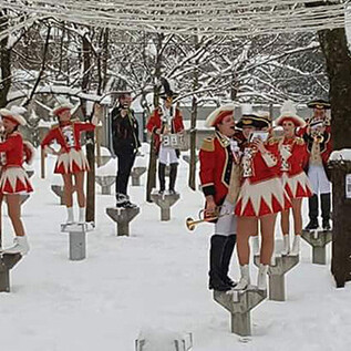 A group of musicians and dancers in winter clothing stands in a snowy environment. They present a festive performance while the landscape is covered with snow. | © 1. Salzburger Faschingsgilde