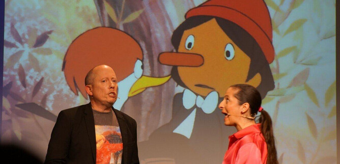 A live performance with two performers on stage. In the background, a scene from an animated film can be seen. | © Sole Goscinski