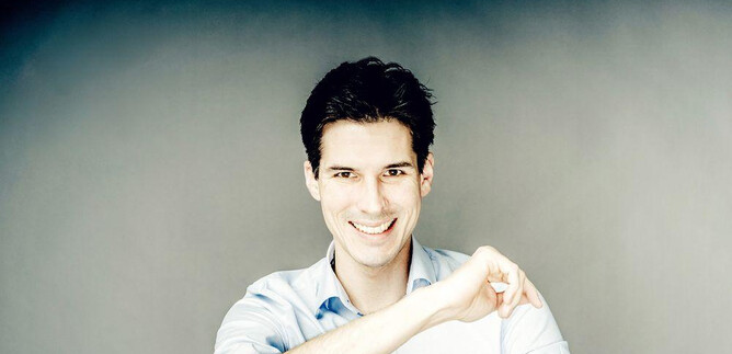 A young man smiles friendly at the camera. He is wearing a light blue shirt and has dark, short hair. | © Andrej Grilc