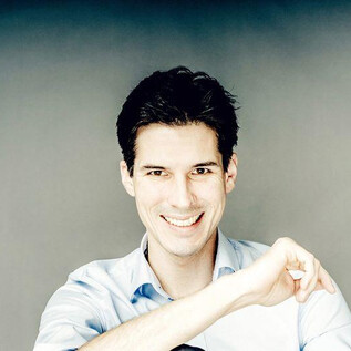 A young man smiles friendly at the camera. He is wearing a light blue shirt and has dark, short hair. | © Andrej Grilc